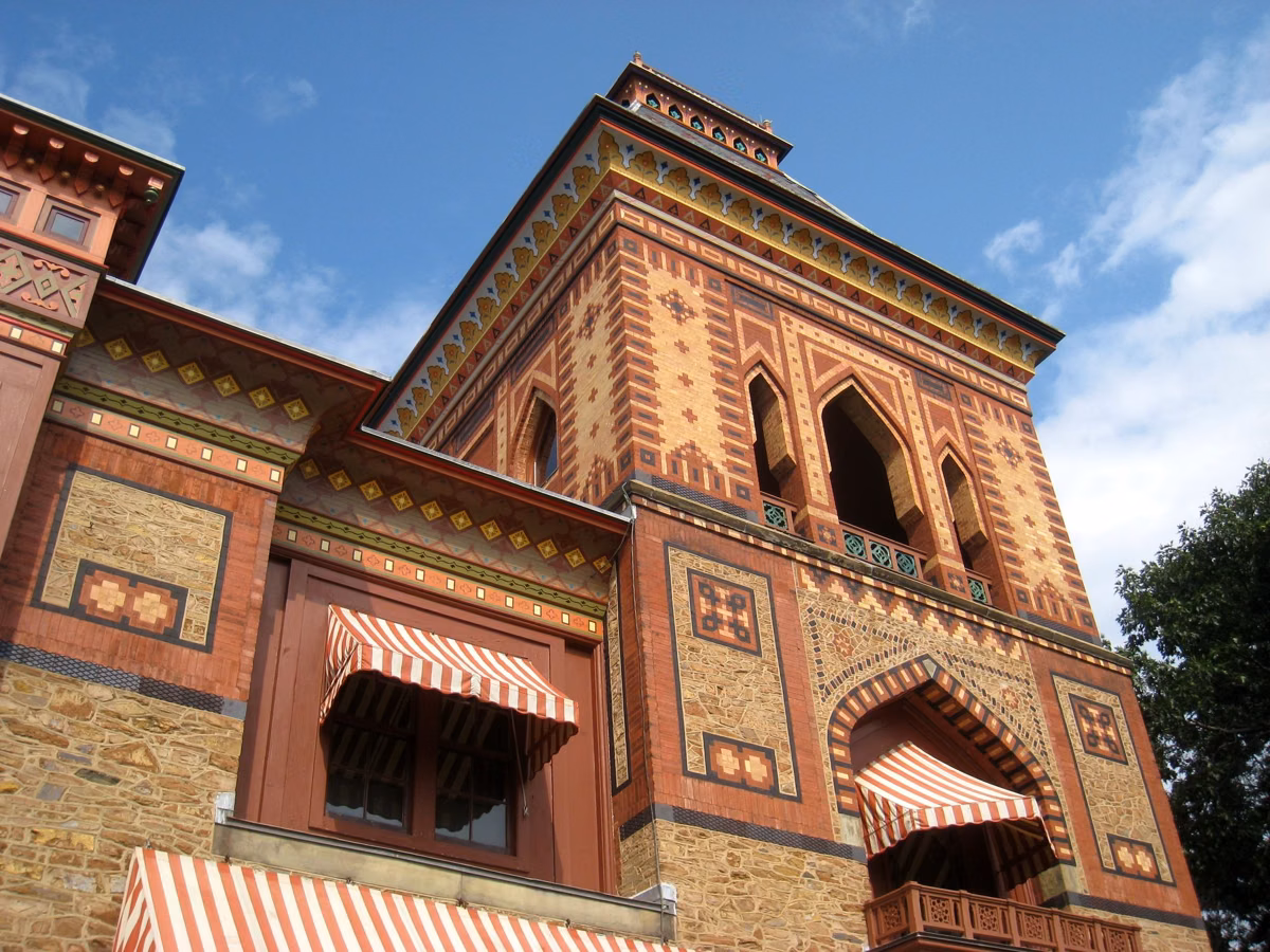 Close view of Olana's tower: patterned brick, pointed arches and striped awnings